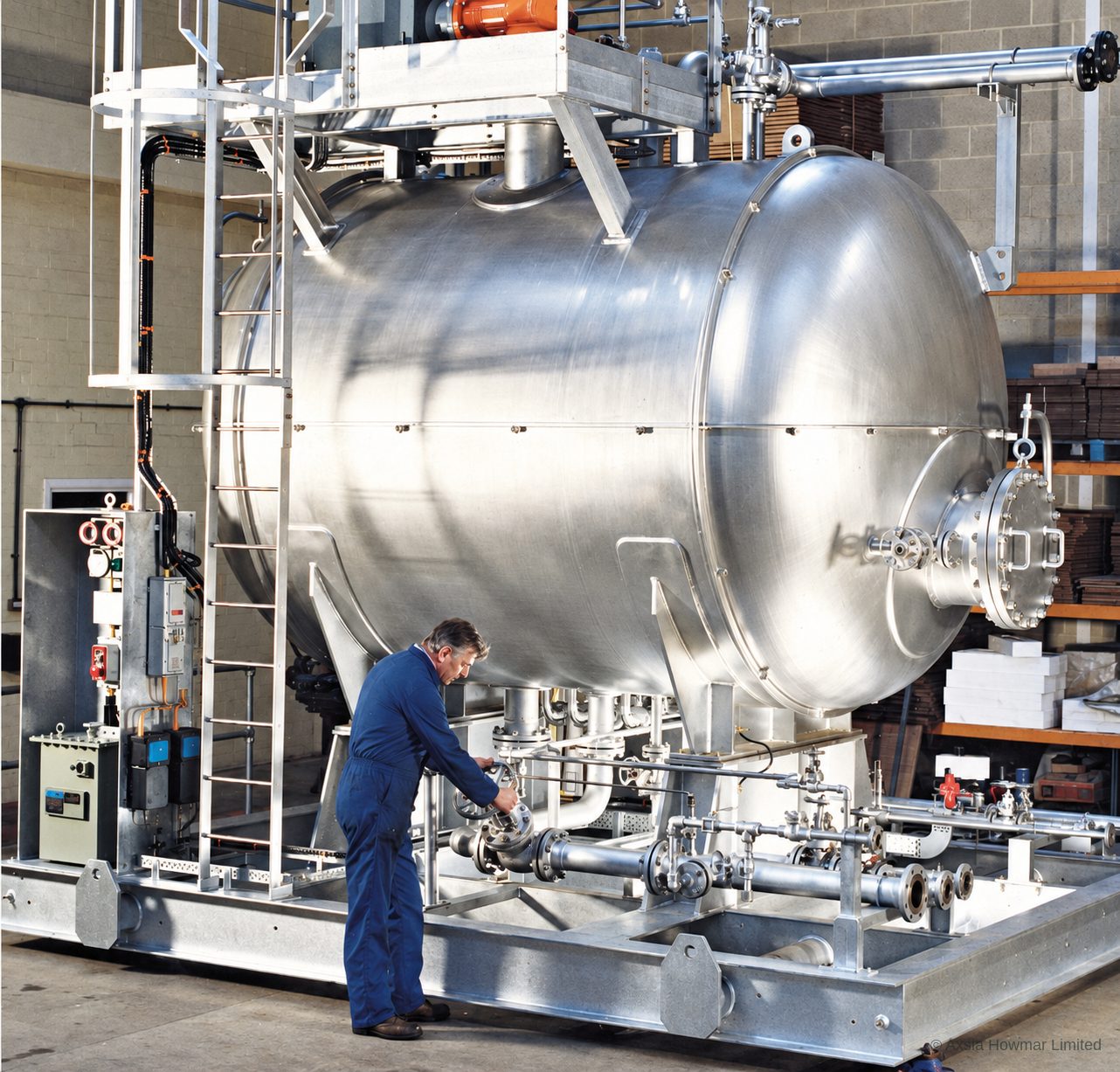 Skid-mounted horizontal electrostatic coalescer package at the fabricator: vessel, top-mounted power unit, control panel and skid piping assembled for testing.